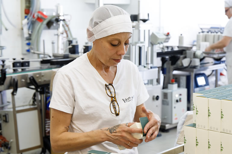 Dott. Solari Staff: Mara inspecting product packaging in a manufacturing environment, showcasing quality control and attention to detail.