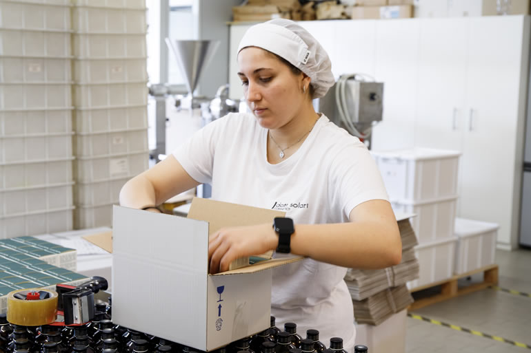 Dott. Solari staff member packaging products. Worker in hair net preparing orders for shipping. Dott. Solari staff at work.
