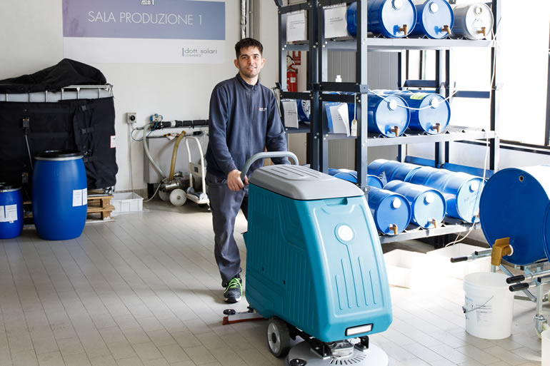 Dott. Solari Staff: Simone operates a floor scrubber in Sala Produzione 1, showcasing industrial cleaning equipment in action.